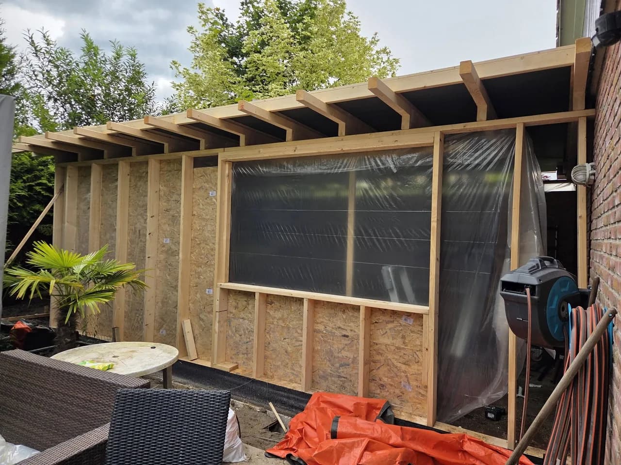 Aanbouw met wandplaten en houten dakbalken in uitvoering