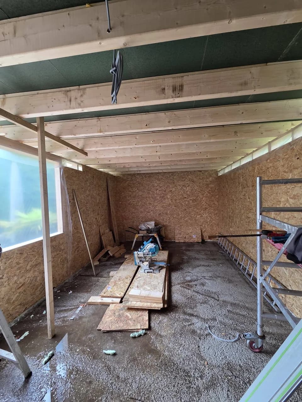 Binnenzijde van de aanbouw met dakbalken en wandplaten