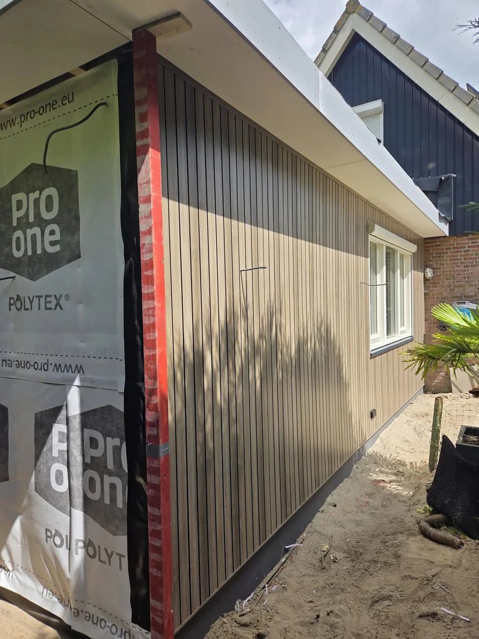 Zijgevel van de aanbouw met houten bekleding in uitvoering