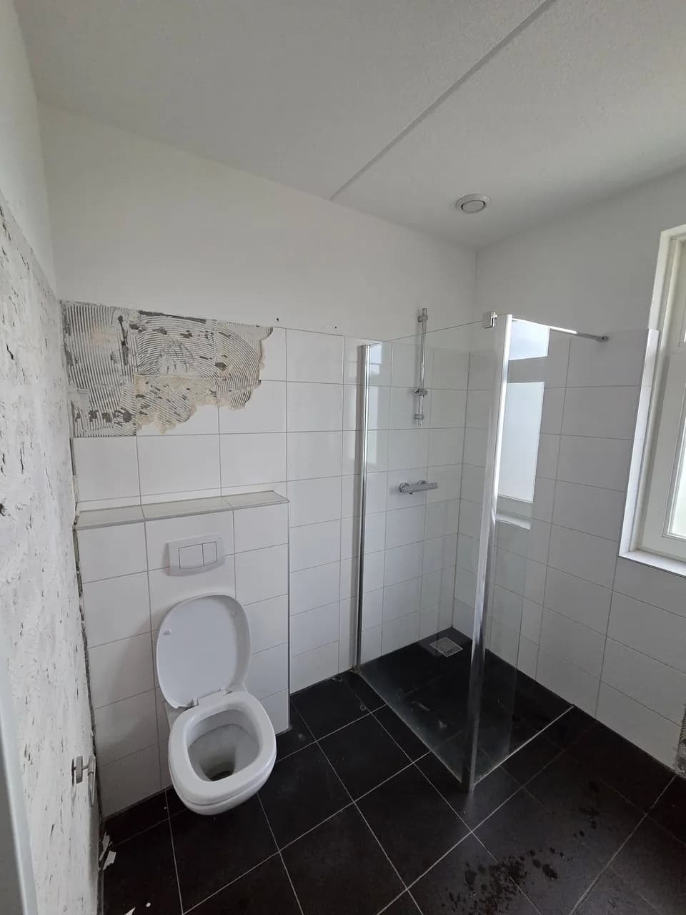 Oude wandtegels gedeeltelijk verwijderd bij het toilet