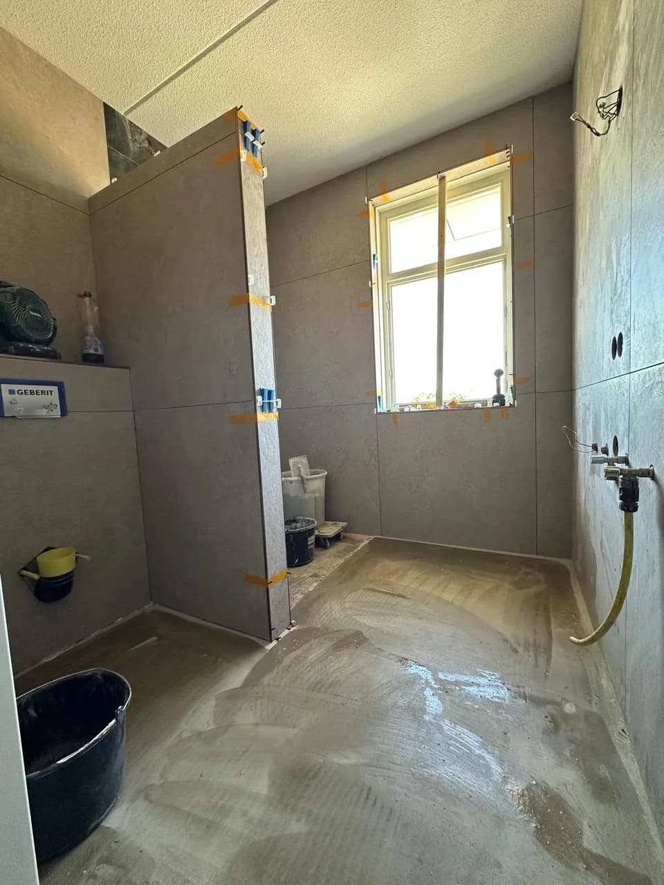 Lichte wandtegels en badkamervloer tijdens de renovatie