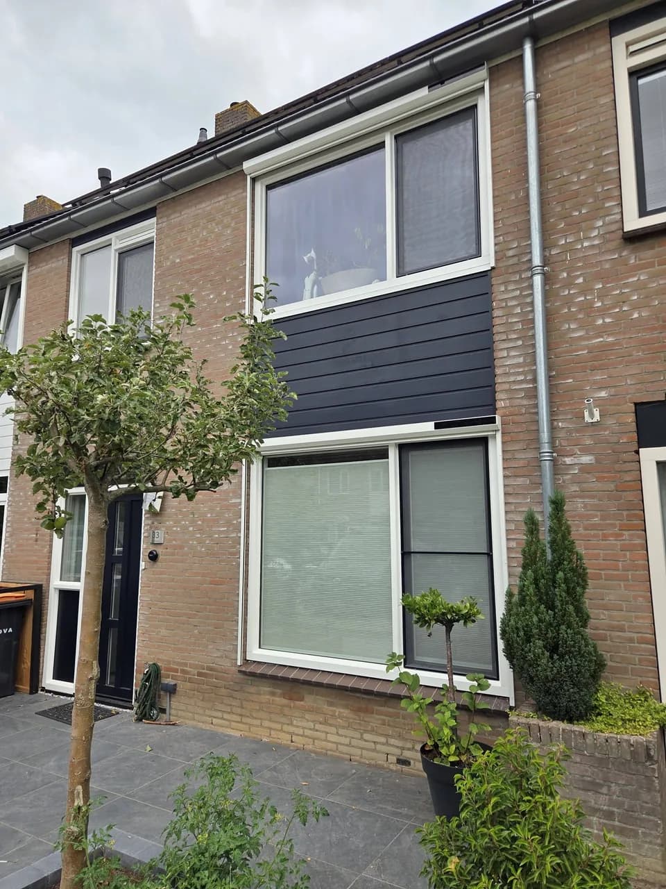 Woning met zip screens bij de ramen en donkere gevelbekleding